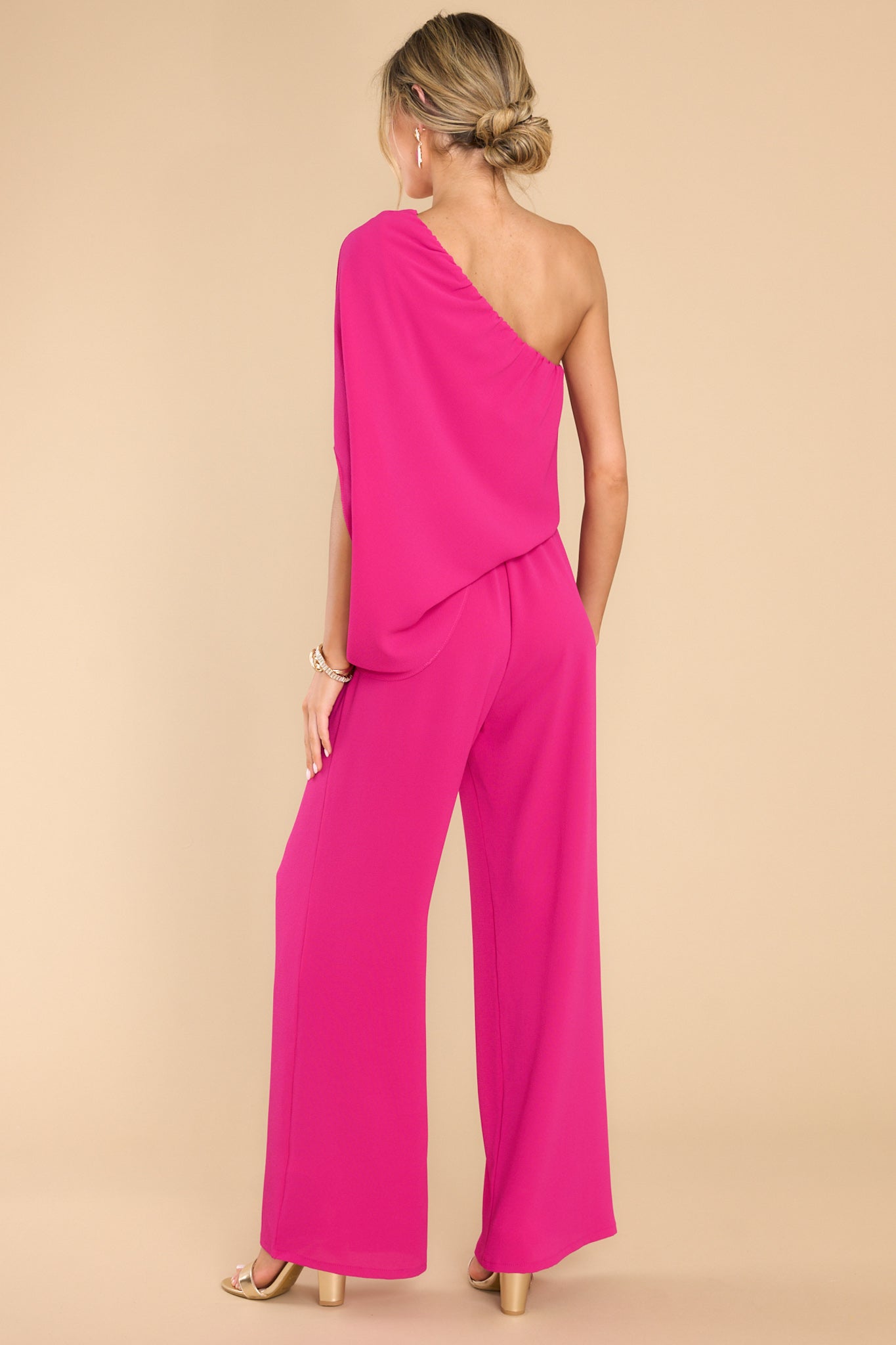 Back view of  this jumpsuit that features an off the shoulder neckline, large dolman sleeve, and an elastic waistline.
