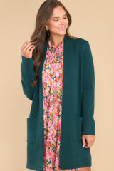 This green cardigan features an open front design, two functional pockets, long sleeves, and a soft knit feel throughout.