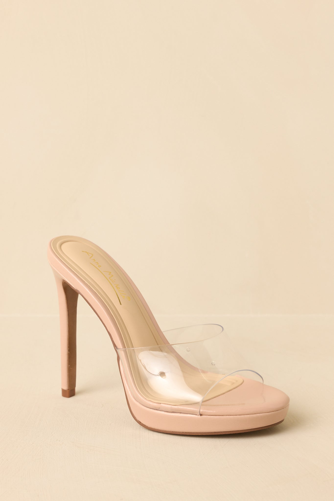 Heels angled to highlight the clear vinyl strap and sleek mule profile.