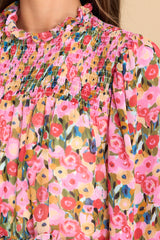 Close up view of this dress that features a high neckline, a keyhole cutout at the back of the neck with a button closure, a sheer smocked section at the shoulders, sheer long sleeves with smocked cuffs, and a flowy skirt.