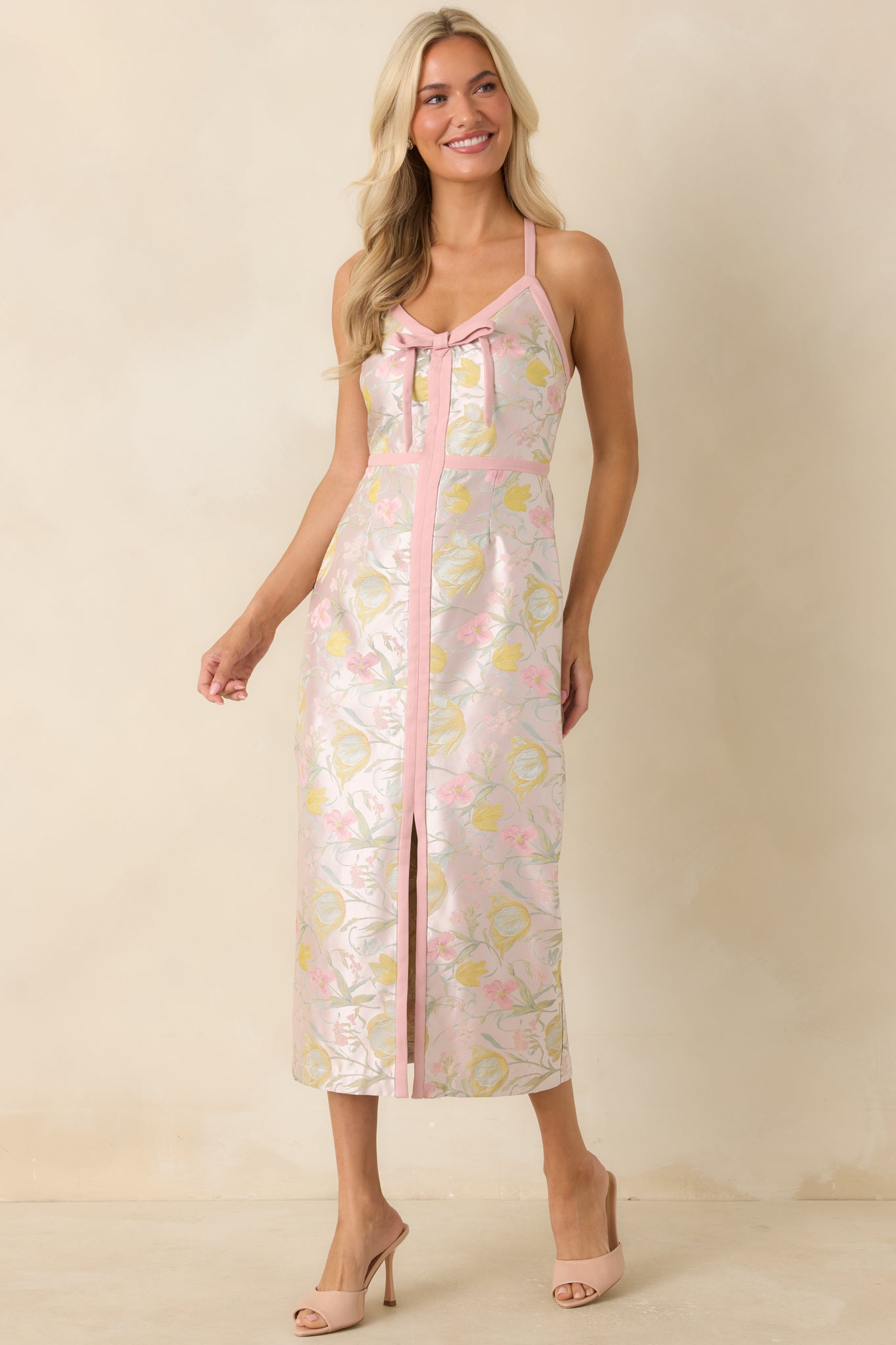 Pink jacquard midi dress highlighting the decorative bow neckline, soft sheen throughout the fabric, and elegant fitted construction.