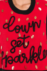Close up view of this sweater vest that features a crew neckline, shiny football sequins, and 