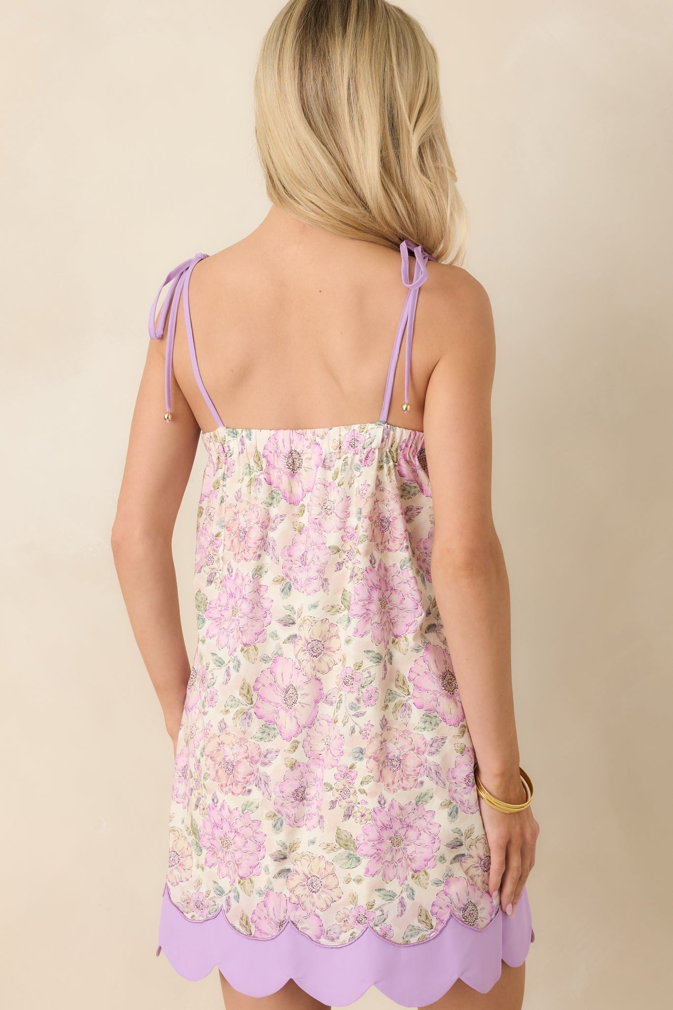 Rear view of lavender floral mini dress featuring tie strap design and relaxed flowing fit.

