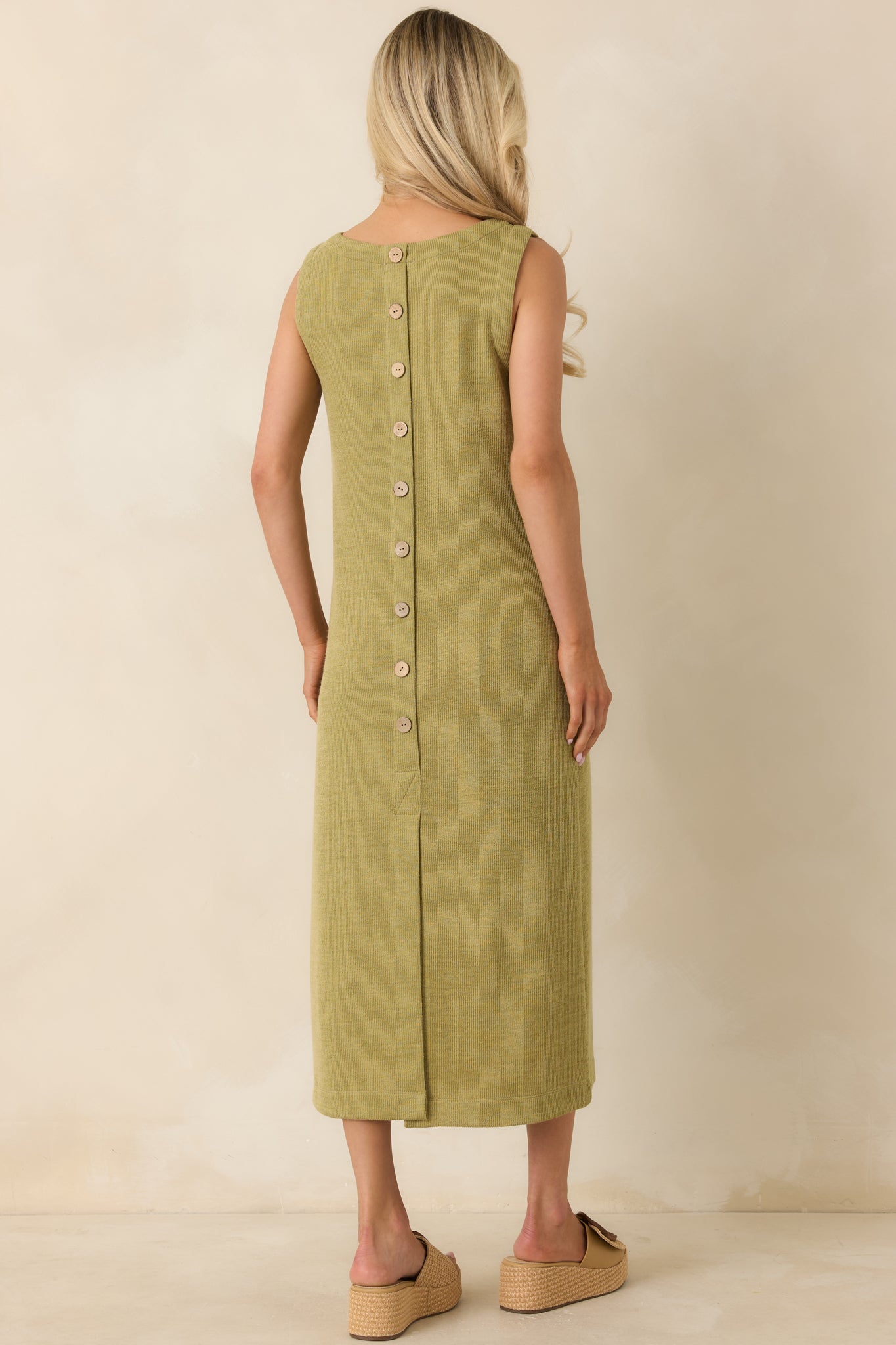 Rear view of the olive green midi dress featuring decorative button detailing and a back slit hem for ease of movement.