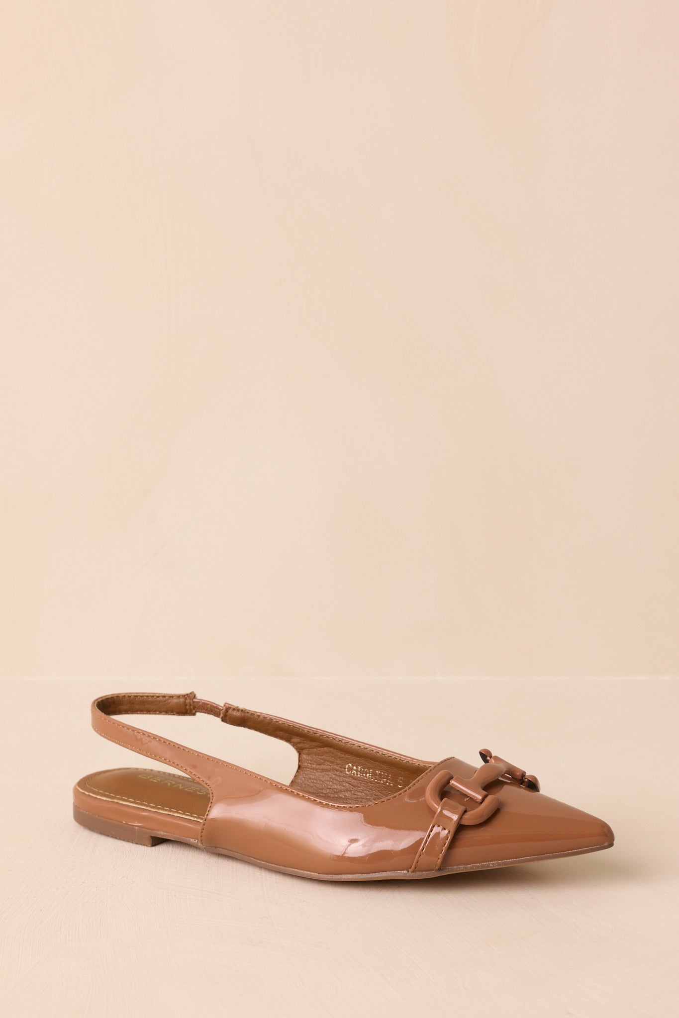 The flats displayed on a beige background at a three-quarter front angle, showing the pointed toe and sleek silhouette.