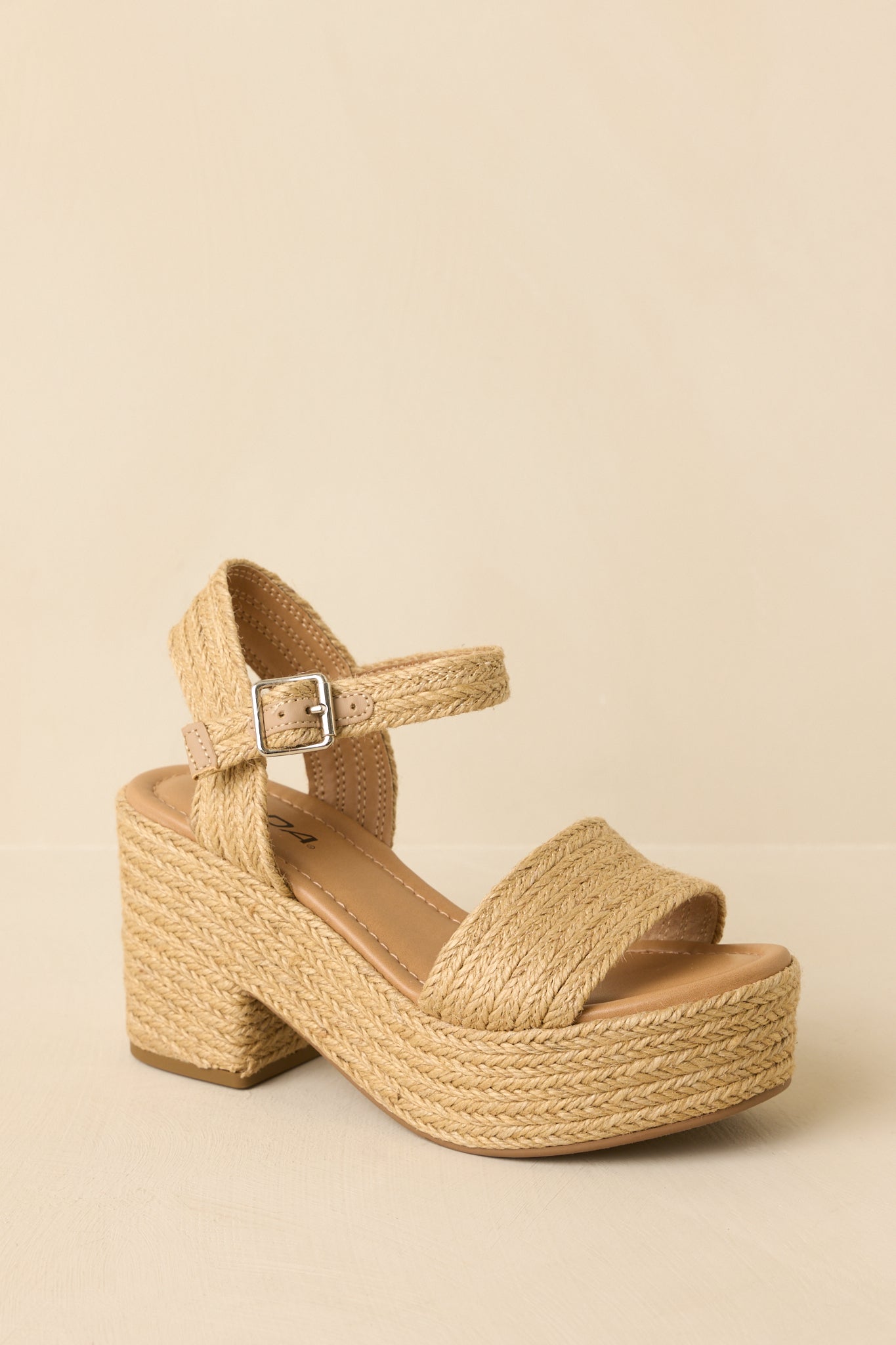 Raffia sandals shown from a low angle emphasizing the textured straps and heel structure.