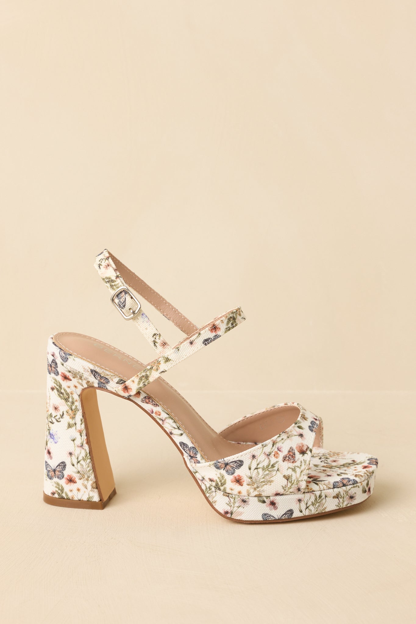 Ivory and floral sandals displayed from the side to show the full block heel and platform sole.