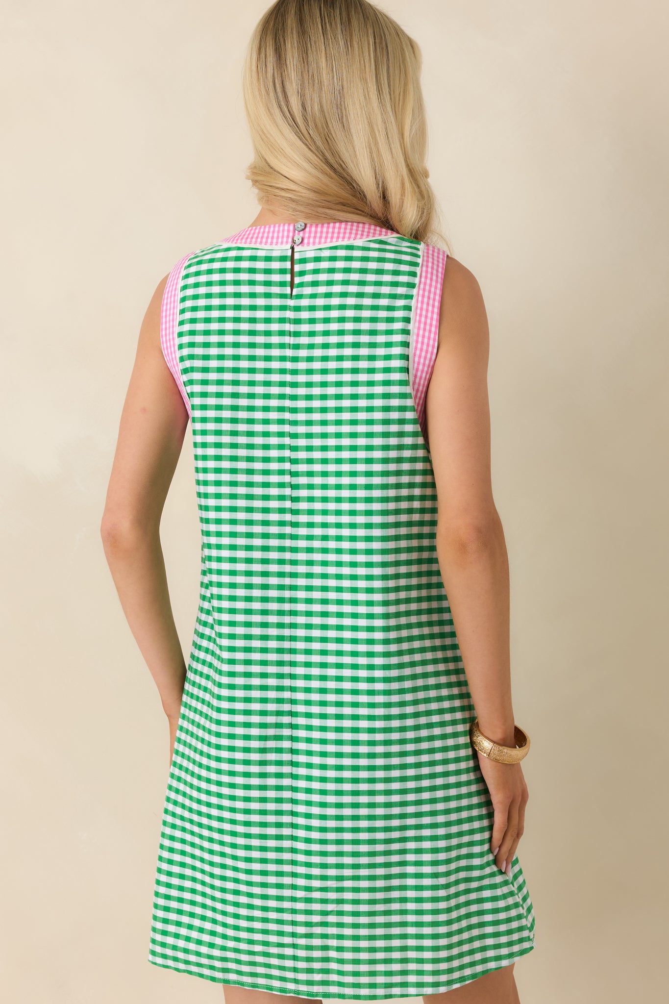 Rear view of the green gingham mini dress featuring a back keyhole button closure and relaxed sleeveless shift silhouette.