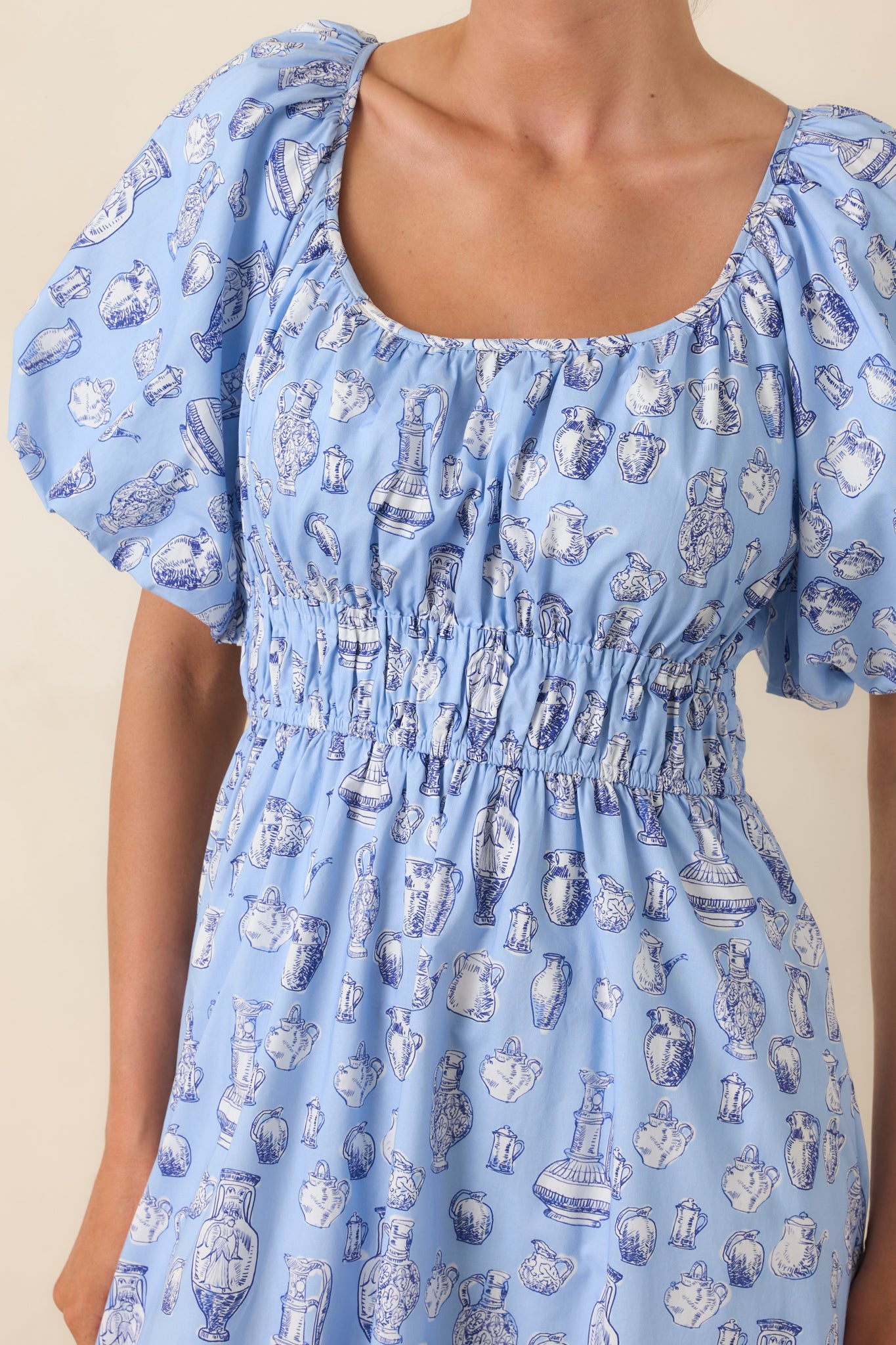 Detailed view of toile print, gathered neckline, and puff sleeve accents on cotton fabric.