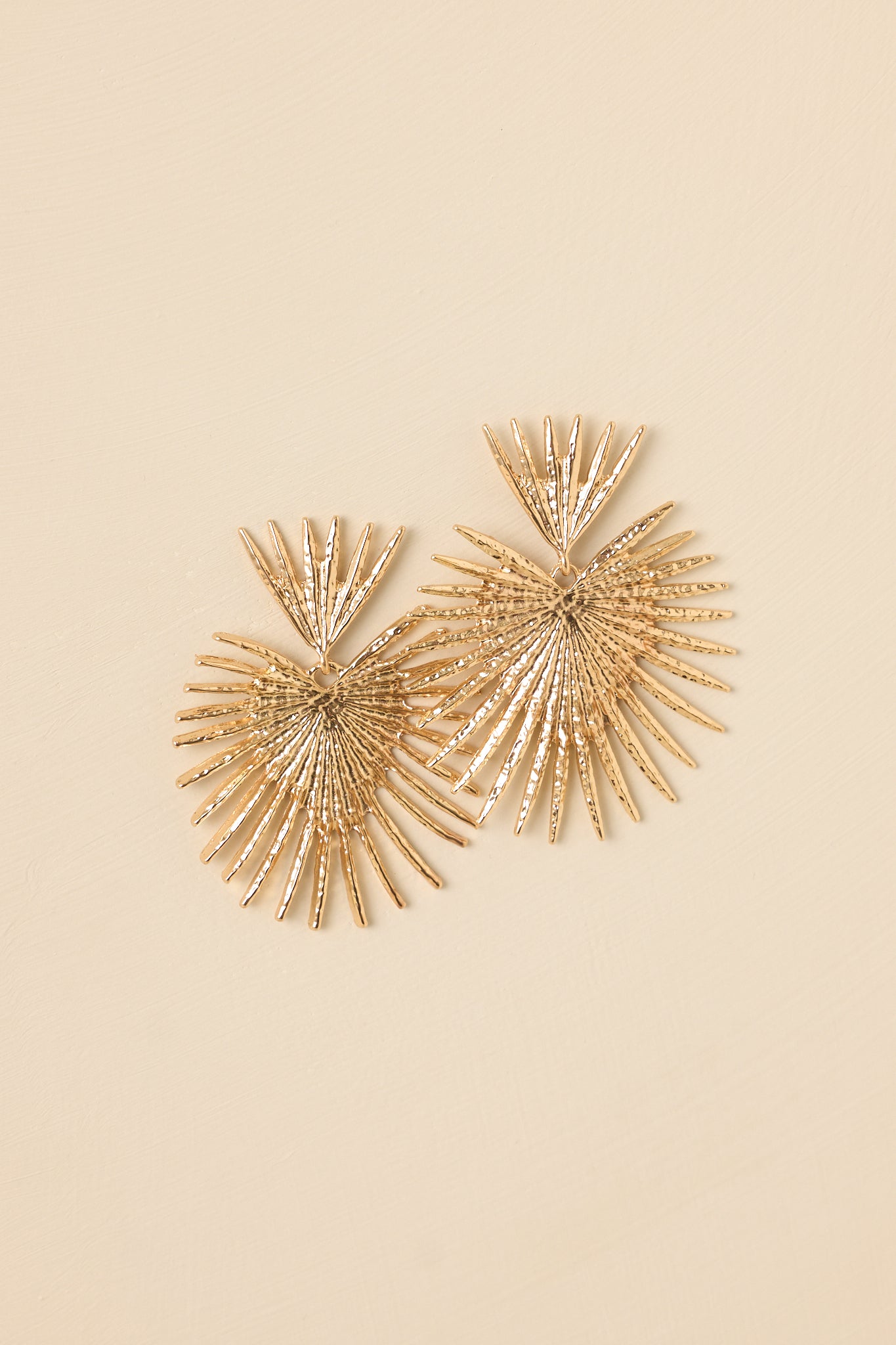 Close-up of the gold-tone fan earrings focusing on the dimensional texture, polished surface, and post-back closure detail.