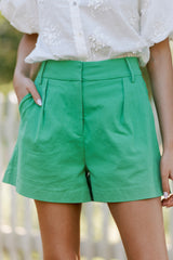 Close up view of these kelly green shorts that feature an elastic insert in the back of the waist, belt loops, and functional waist pockets.