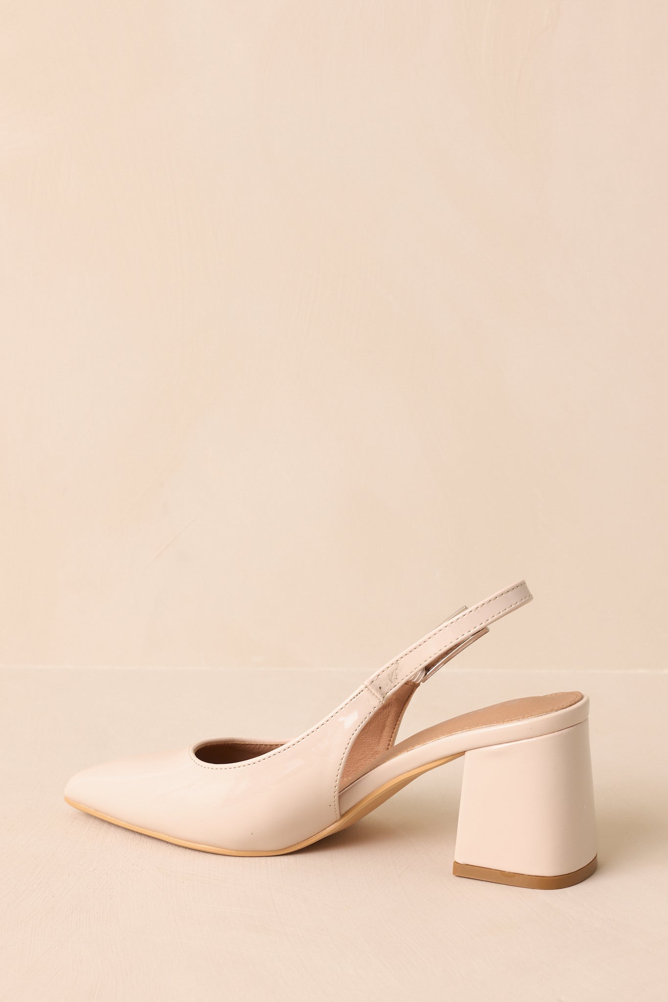 Rear view of beige heels highlighting slingback strap and block heel.