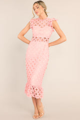 This pink crochet lace midi dress features a high neckline with an illusion sweetheart neckline, ruffled shoulders, a peek-a-boo waistline which gives way into a sheath silhouette fit, and a flounced hem. 