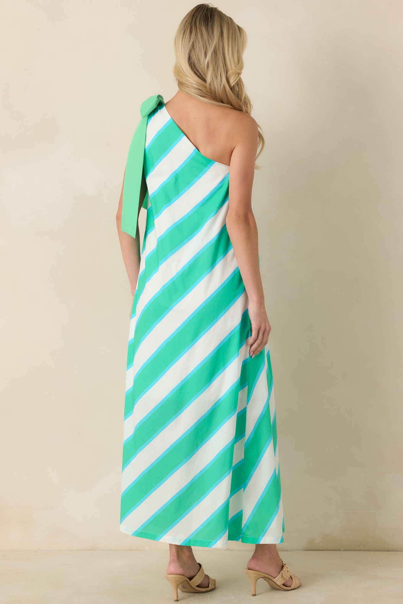 Rear view of the aqua and mint striped maxi dress featuring a flowing silhouette, fully lined design, and clean one-shoulder styling.