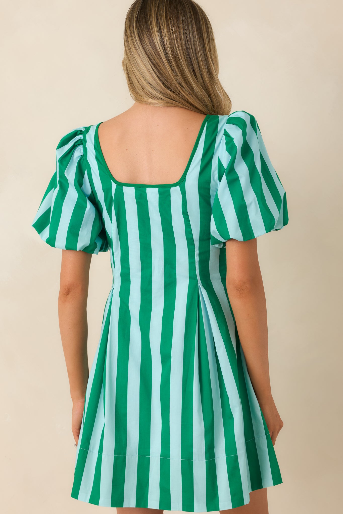 Back view of the cotton mini dress featuring a fitted silhouette, puff sleeves, and concealed side zipper for a smooth finish.