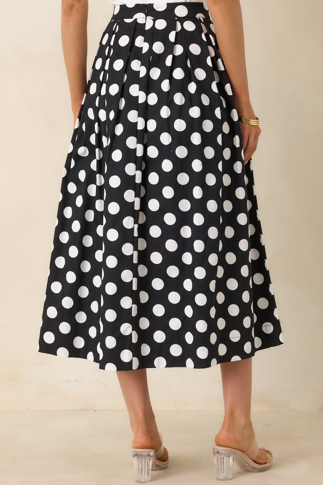 Back view of black and white polka dot maxi skirt showcasing pleated A-line shape and concealed zipper closure.