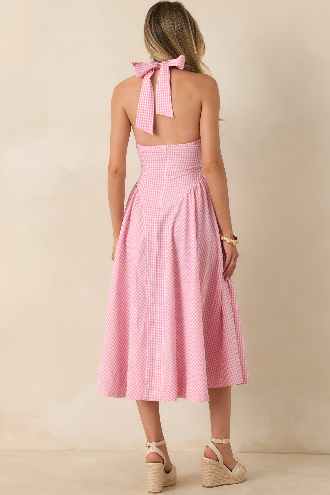 Rear view of the pink gingham midi dress featuring an open back design, self-tie bow closure, and concealed zipper detail.