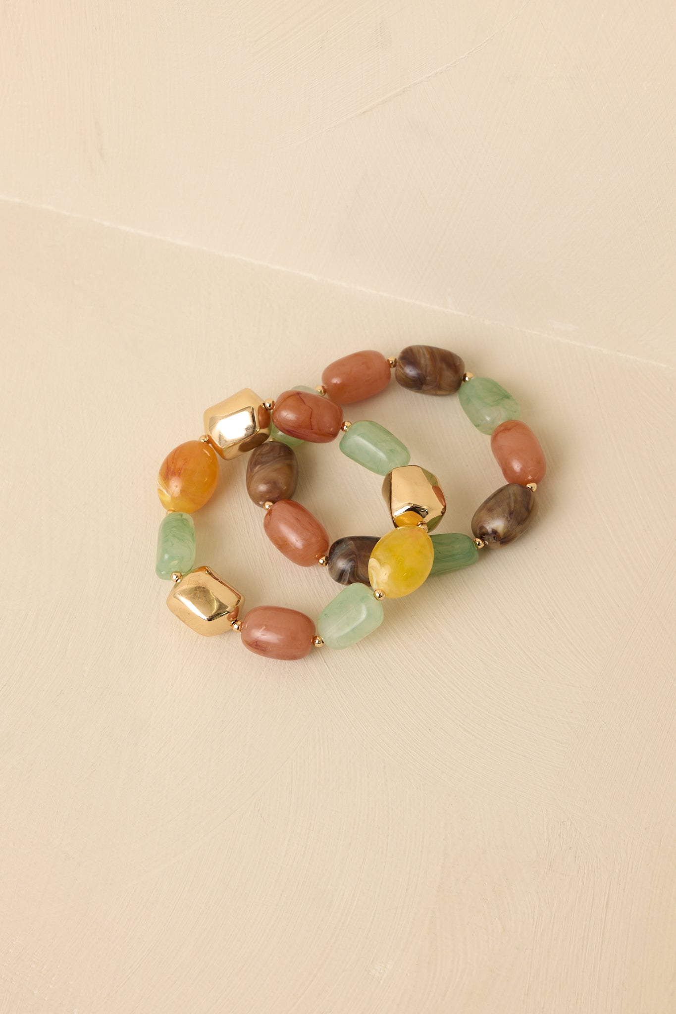 Close-up of gold multi bracelet set showing bead texture, color variation, and gold-tone metal accents.