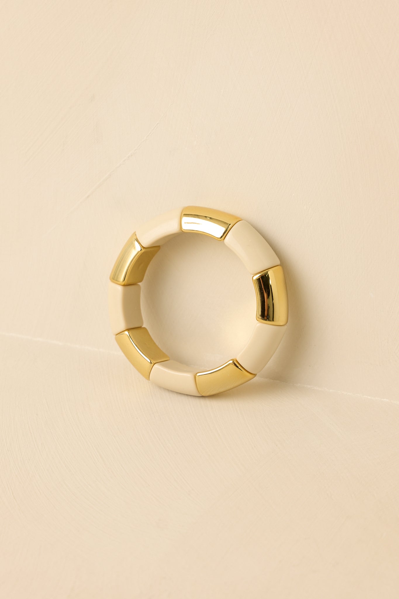 Angled view of bracelet on beige background emphasizing sculptural, bold bead design.