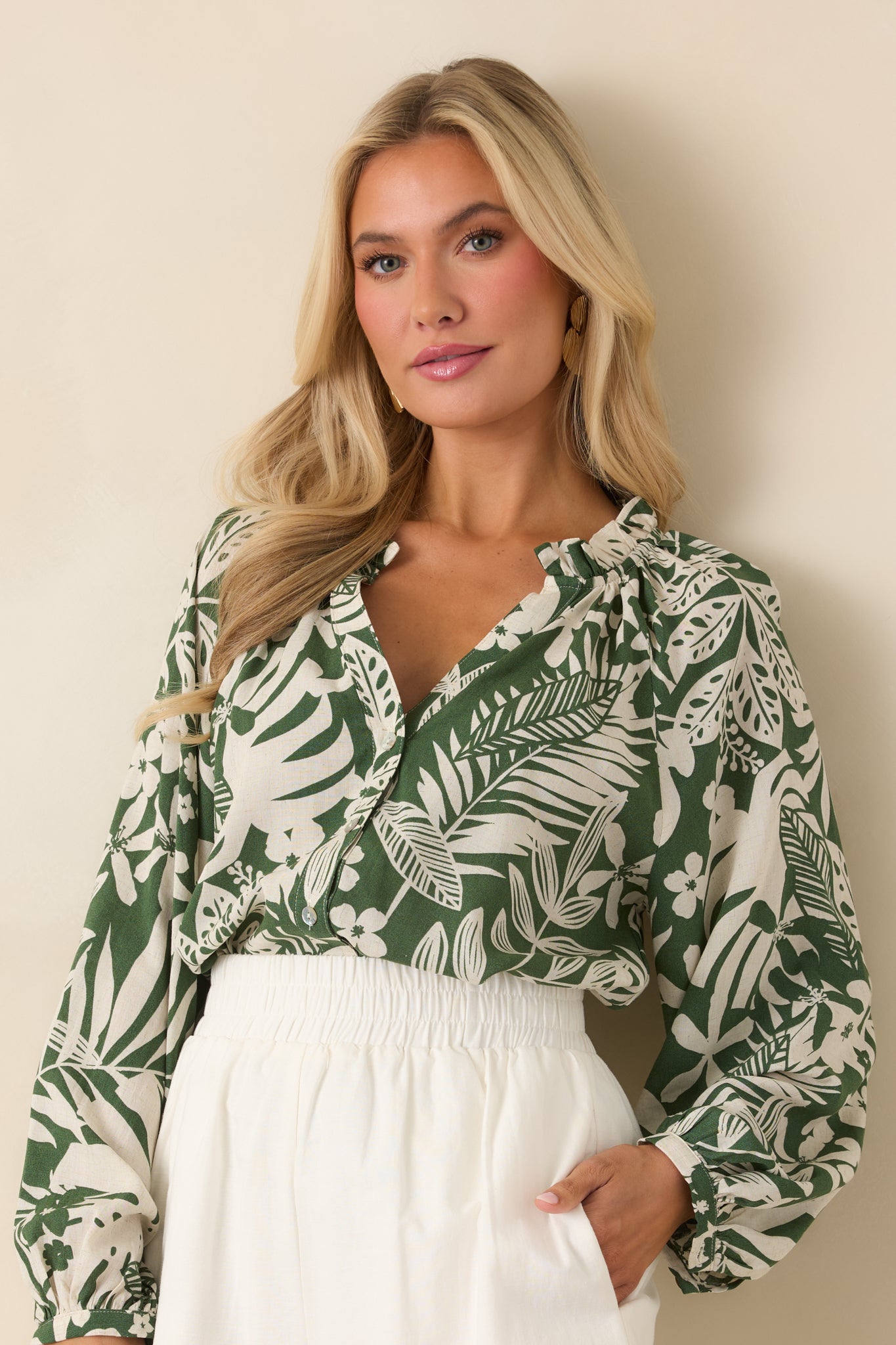 Cropped view of green tropical top highlighting ruffled V-neckline and button-front detail