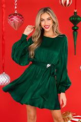 Front view of this dress that features a round neckline, a keyhole with a button closure on the back, flowy sleeves with smocked cuffs, an elastic waistband, a self-tie, and a flowy skirt.