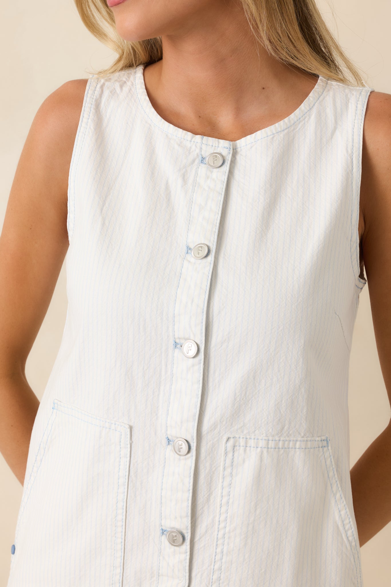 Close-up of ivory mini dress highlighting mother-of-pearl buttons, stripe detailing, and lightweight cotton weave.