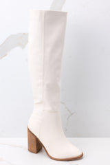 Outside view of white boots featuring a subtle pointed toe, and a faux leather finish. 