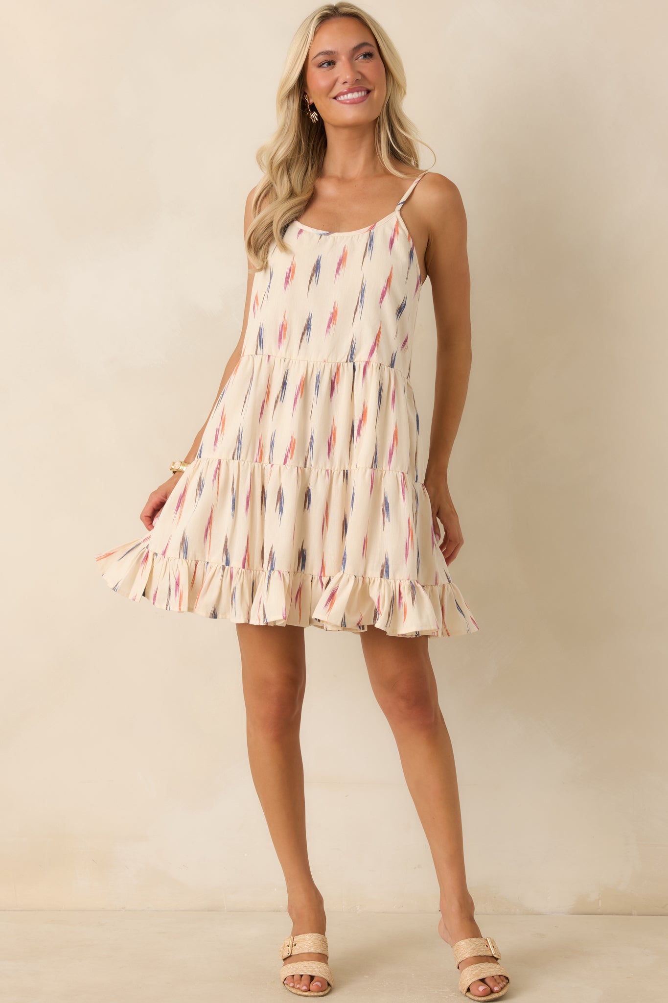 Ivory printed mini dress showcasing a sleeveless silhouette, scoop neckline, and breezy tiered skirt.