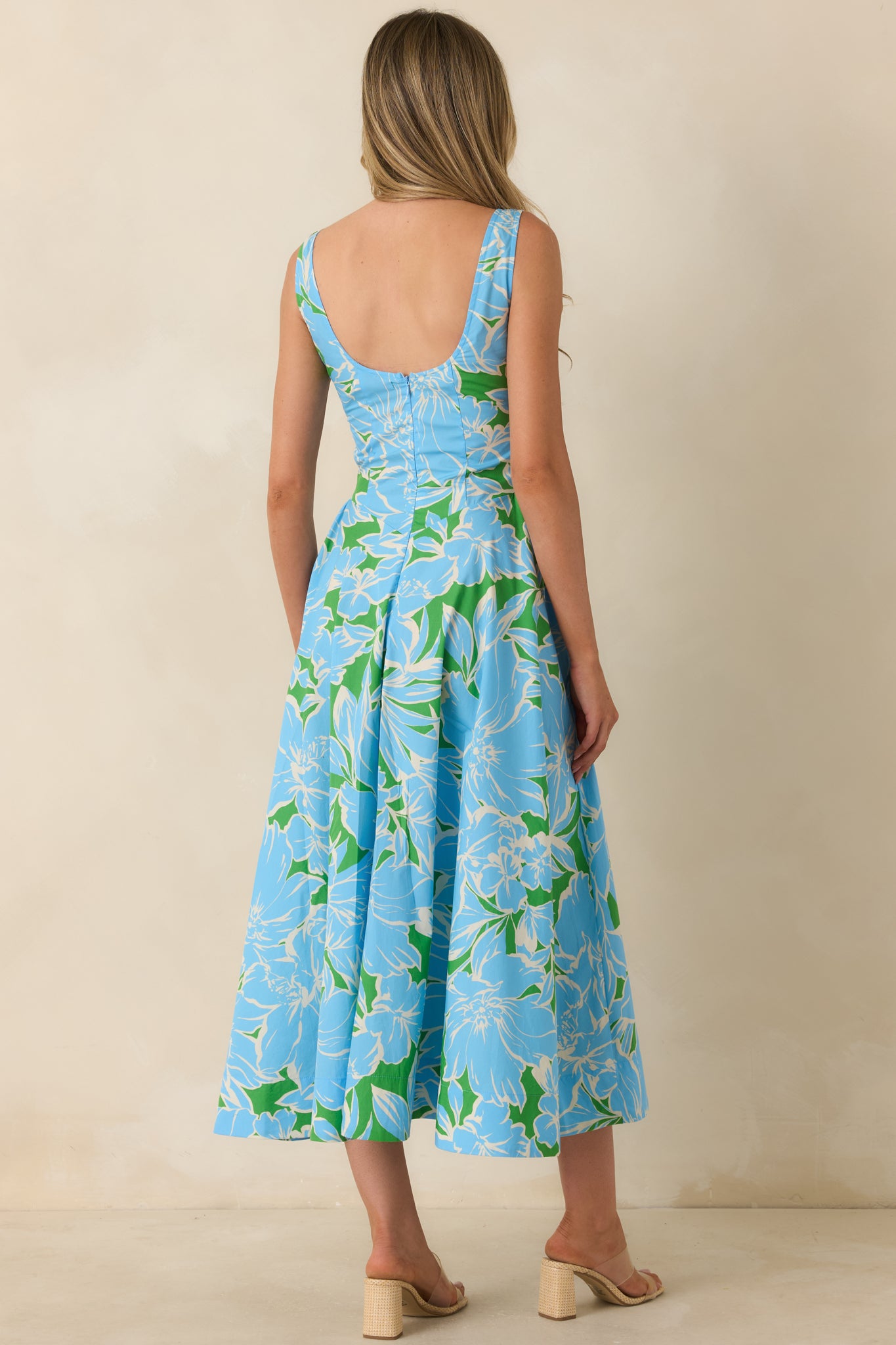 Rear view of the floral cotton midi dress featuring a scoop back design, sleeveless silhouette, fitted bodice, and full midi-length skirt.
