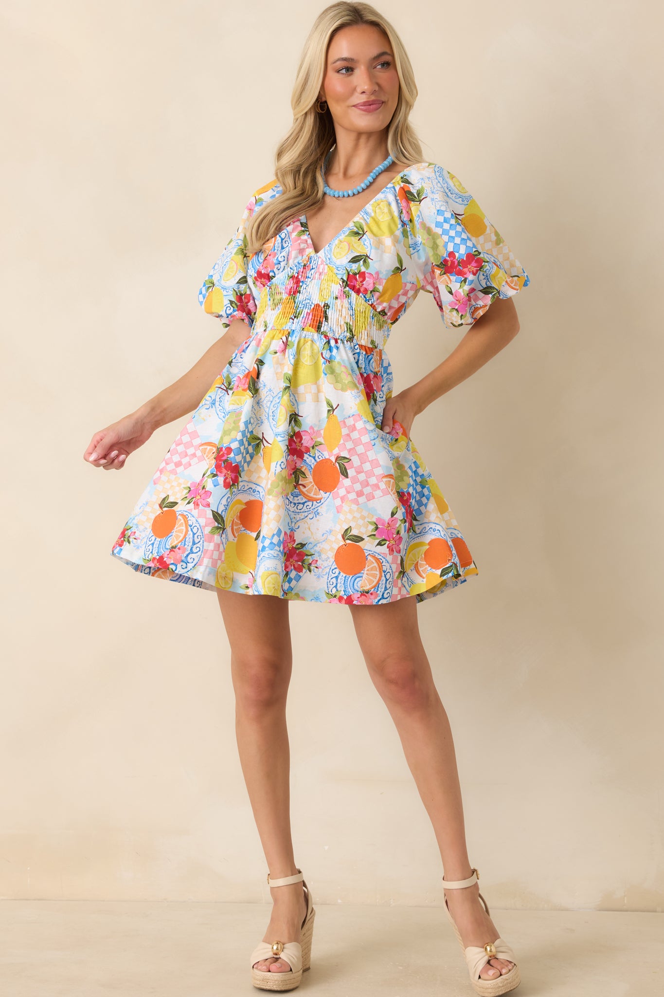 Mini dress in a multi citrus print crafted from a linen cotton blend, featuring a surplice V-neckline and vibrant fruit-inspired pattern throughout.