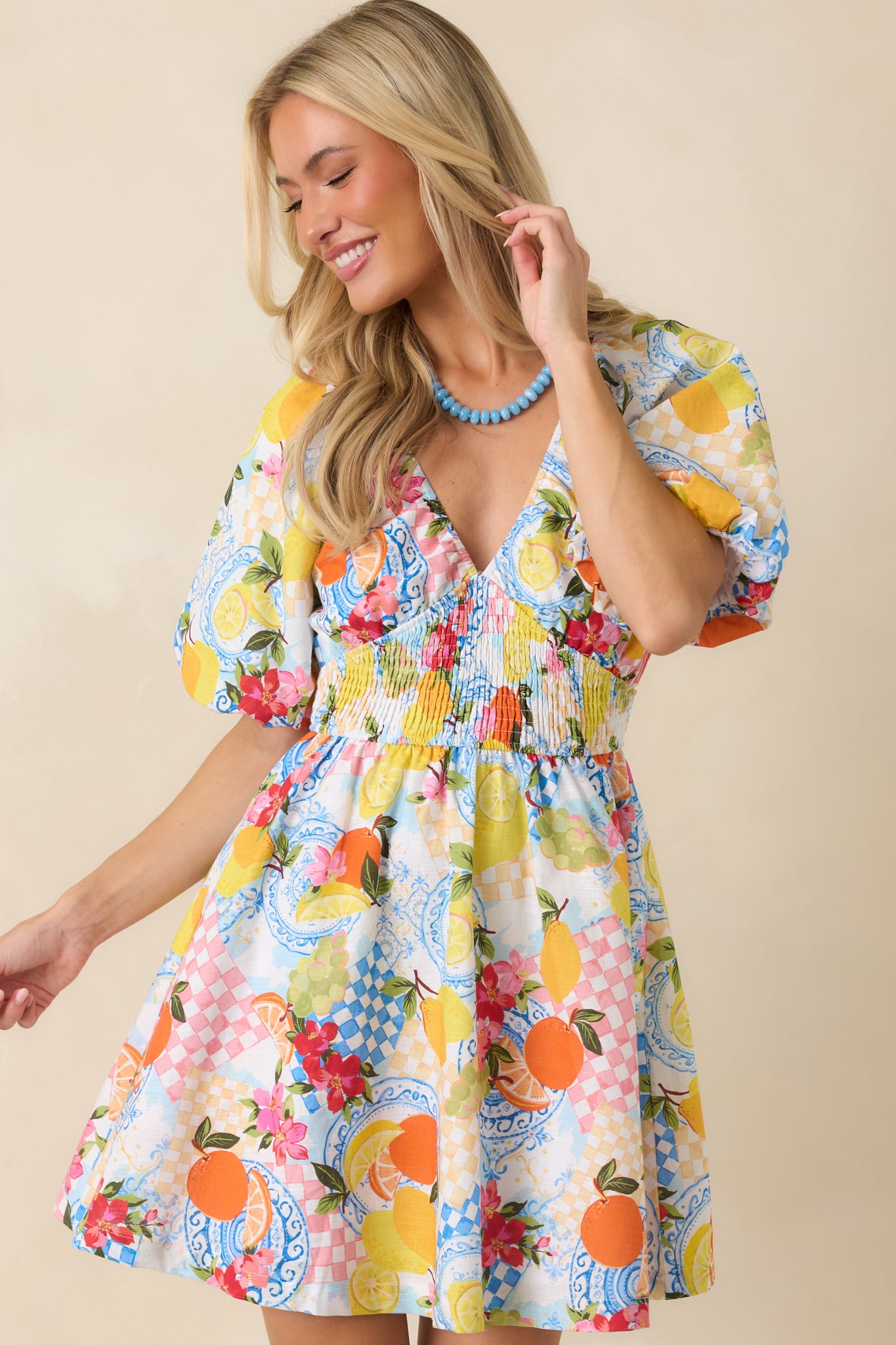 Smocked empire waist detail on a citrus print mini dress showing soft gathered texture and flexible stretch.