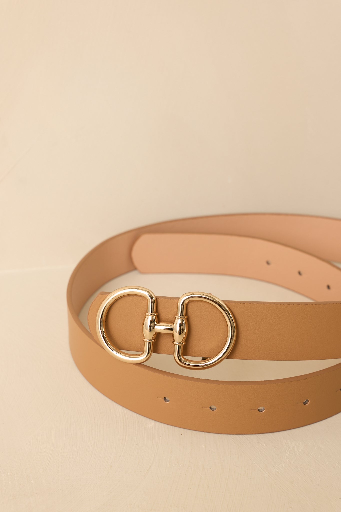 Detailed close-up of light camel belt showcasing gold-tone double ring buckle and refined strap texture.