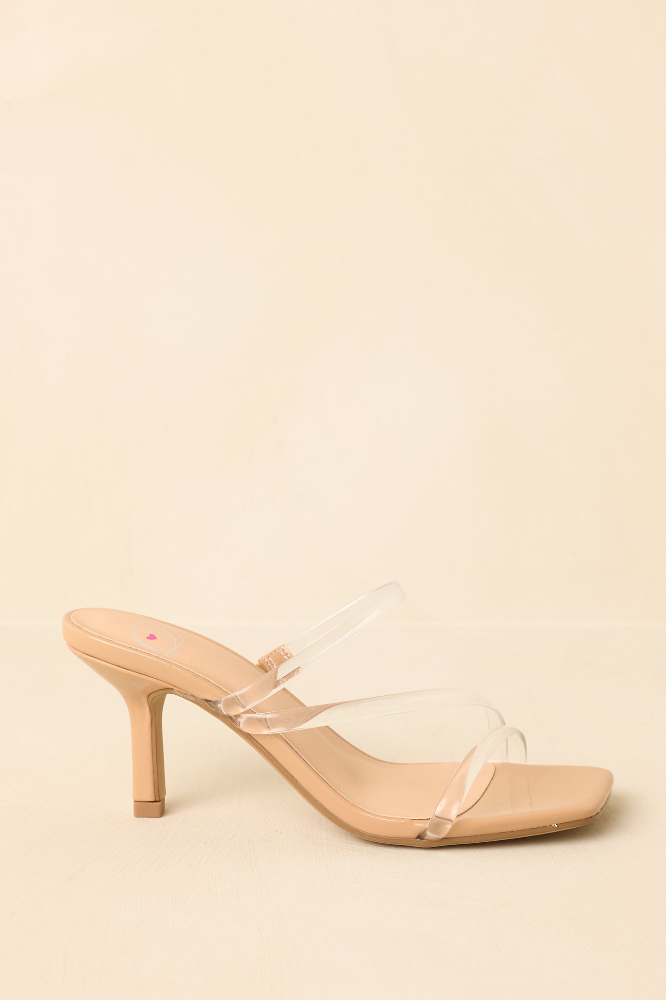 Angled side view of the nude slip-on heels highlighting the structured heel and clean lines on a beige backdrop.