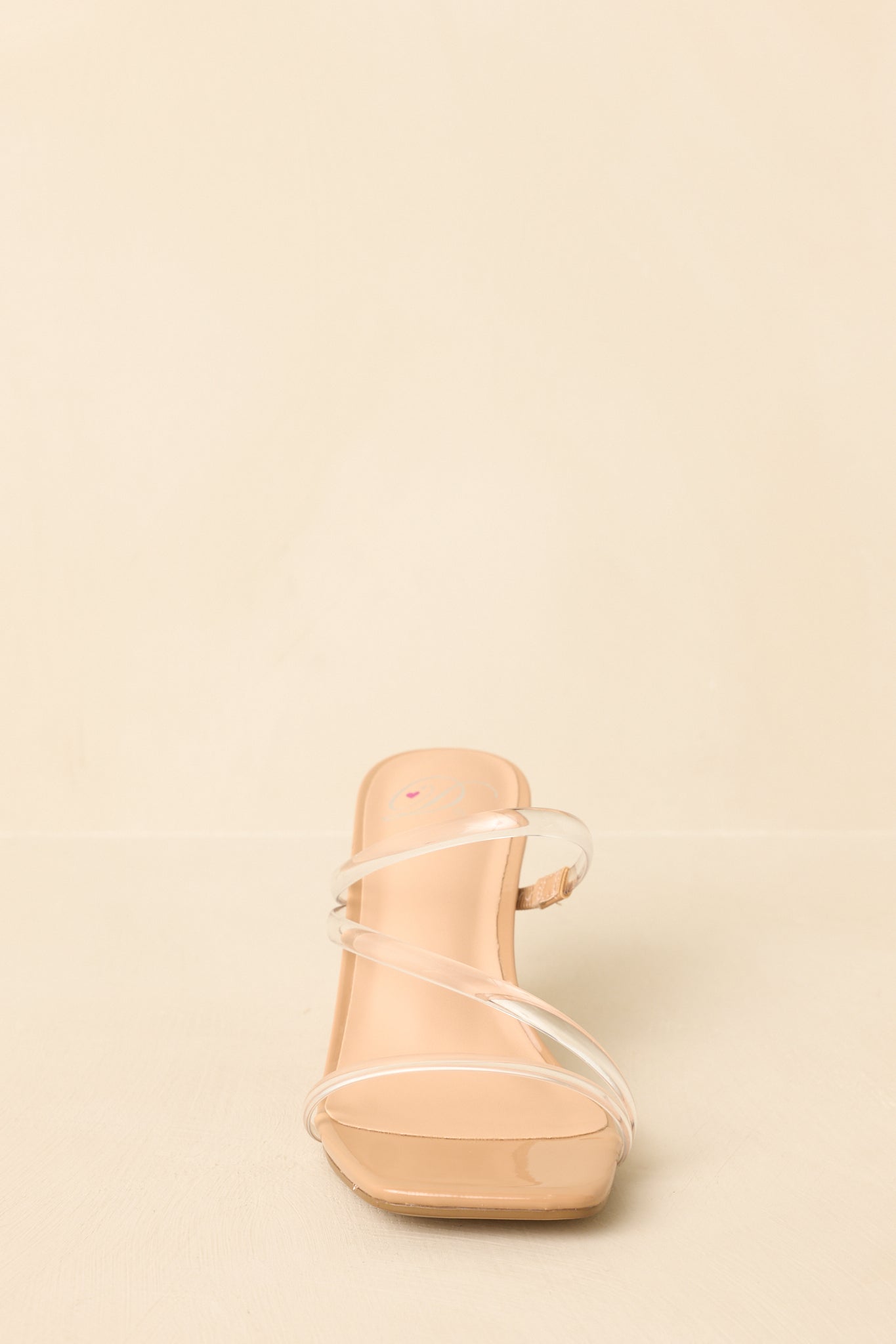 Front-focused cropped image highlighting the transparent straps and clean nude base of the slip-on heels.