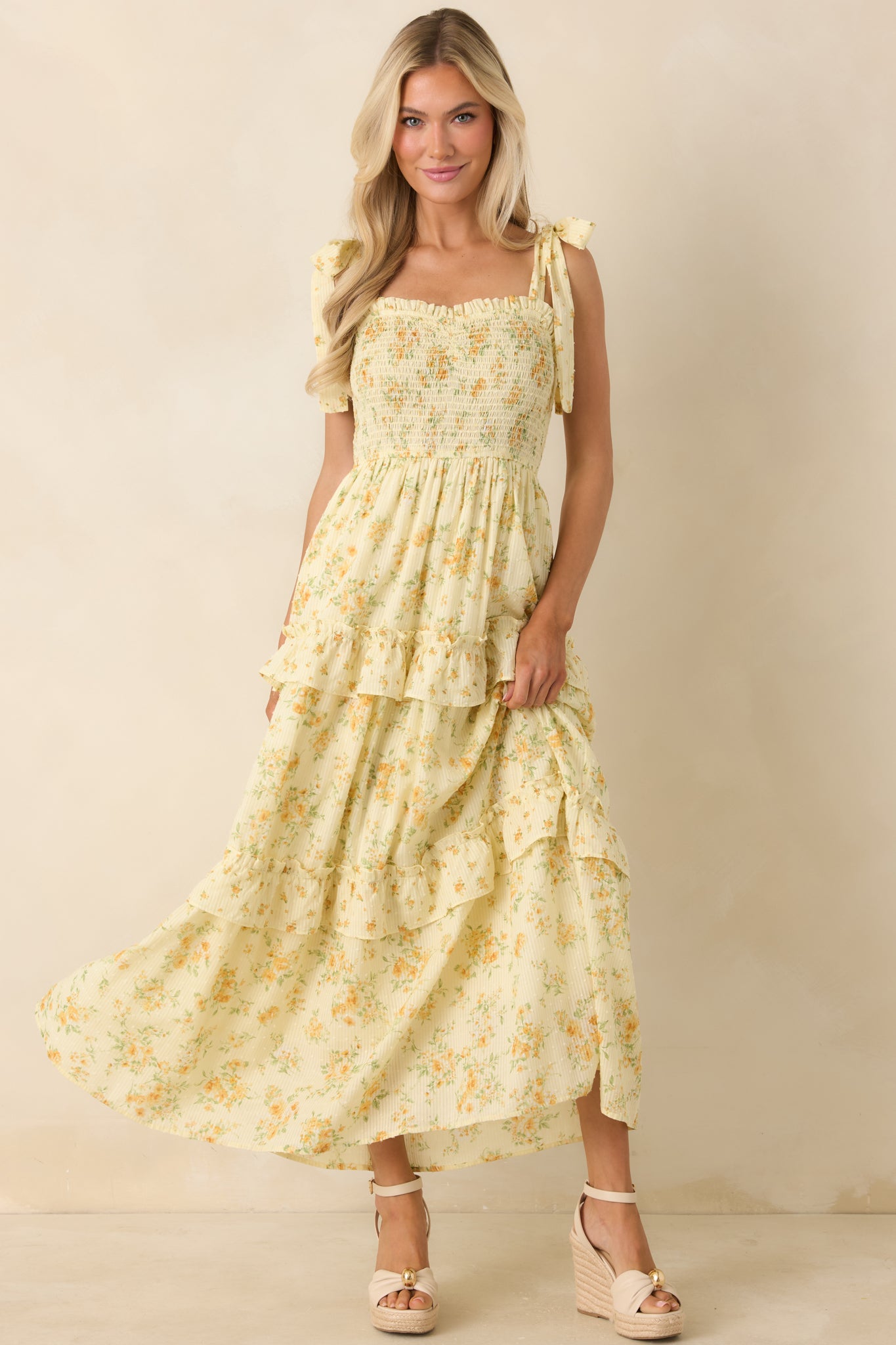 Smocked bodice floral dress with delicate print and flowing, layered silhouette.