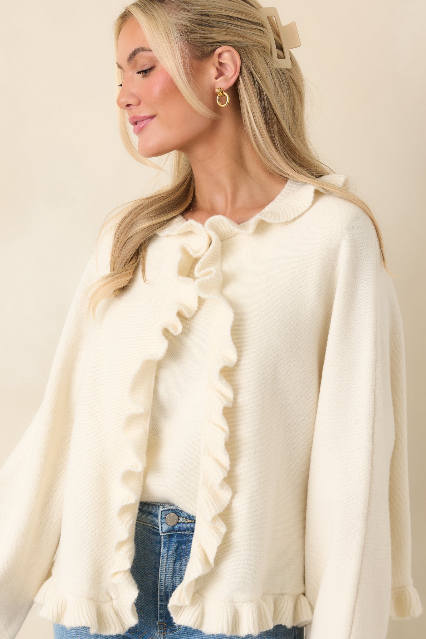 Ivory cardigan with long sleeves and ruffle accents at the neckline and hem.
