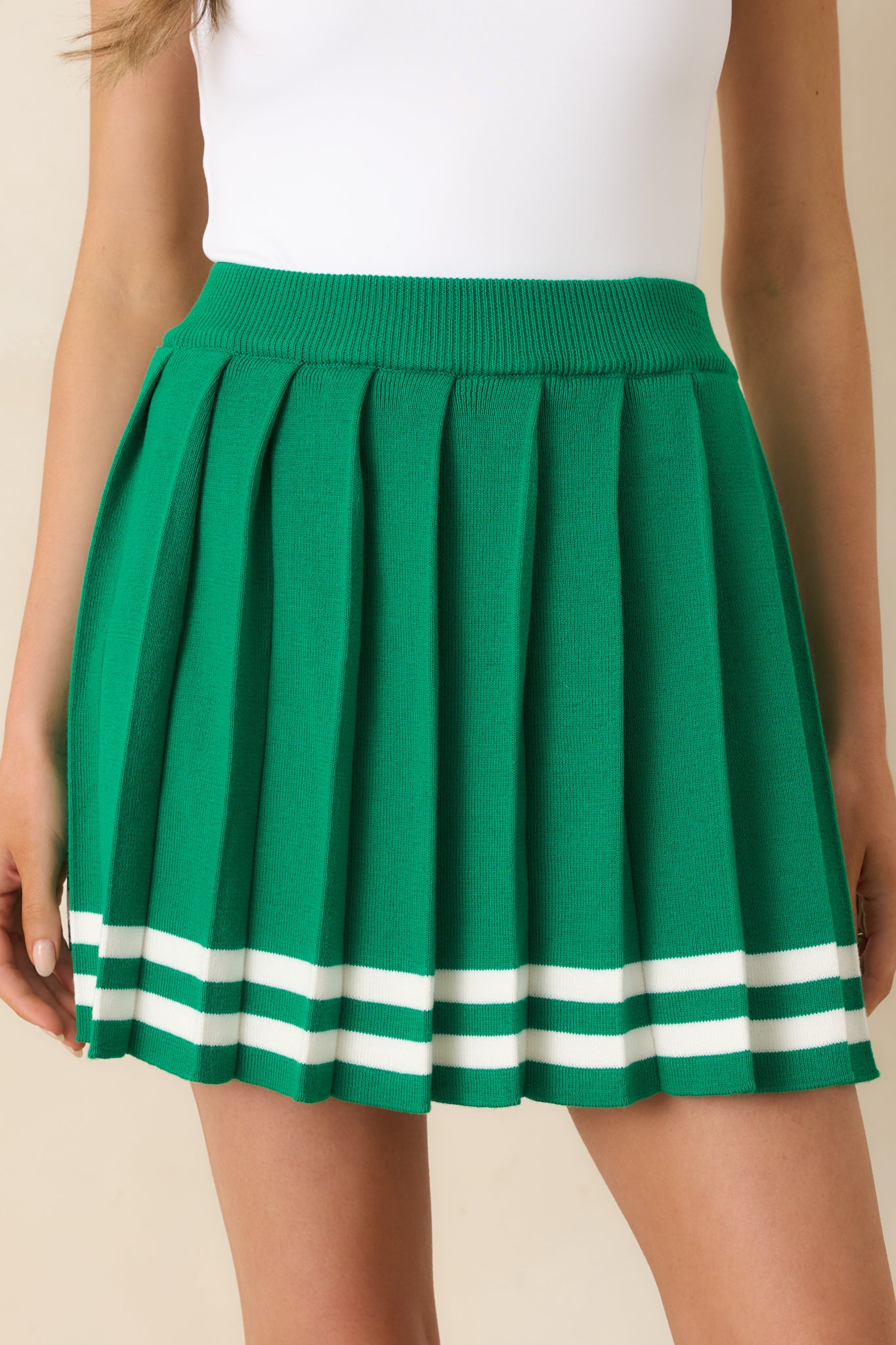 Pleated green skirt, highlighting the elastic waistband and smooth knit texture.