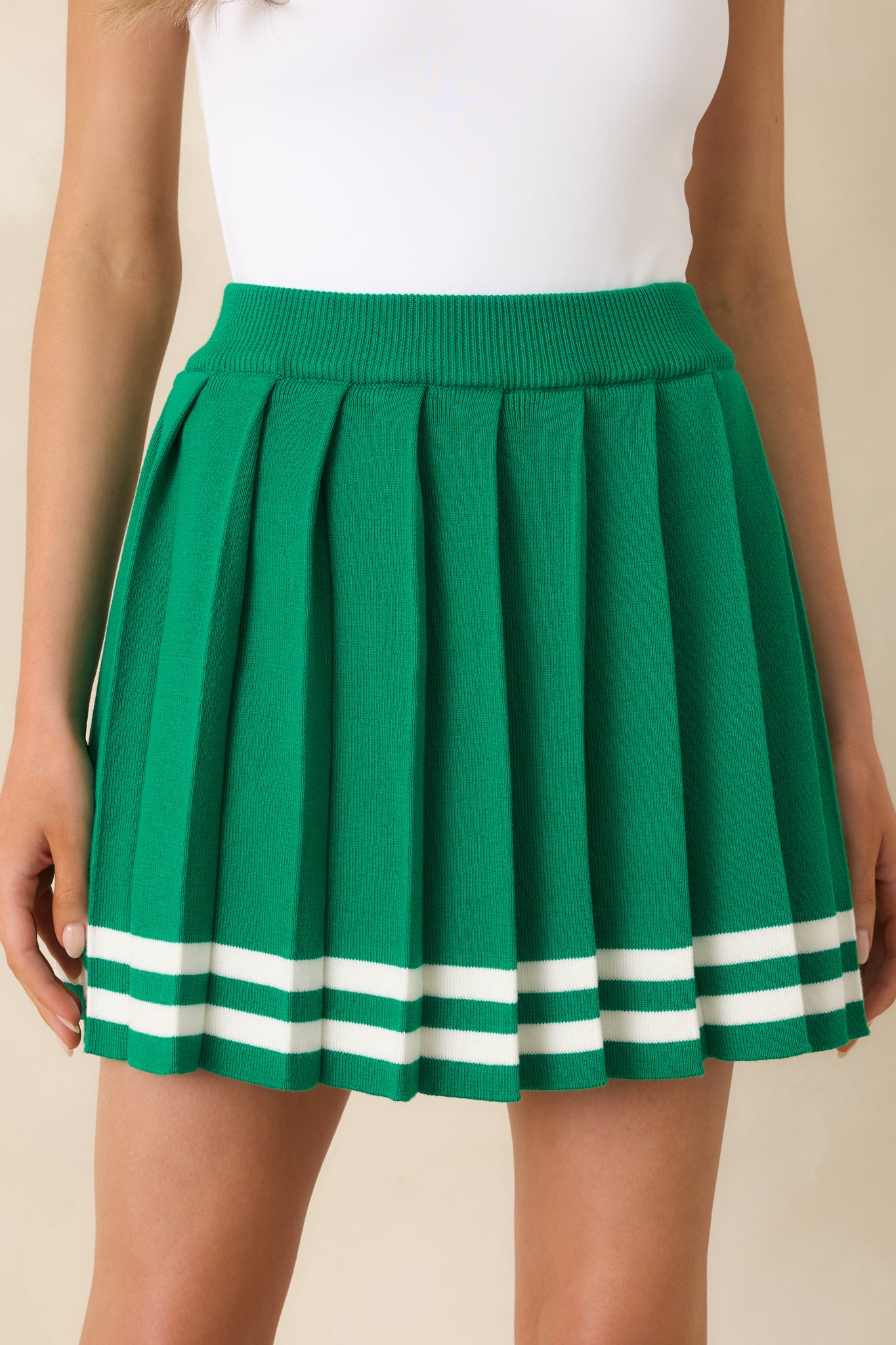 Detailed view of the pleated knit fabric, featuring white stripe trim at the hem.