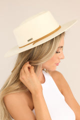 This off white hat features a round telescope crown with a flat brim and a leather chinstrap around the crown.