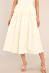 Front view of this skirt that features a high waisted design, an elastic insert at the back of the waist, and intricate pleats around the hipline.