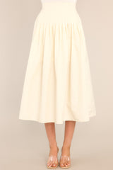 Full front view of this skirt that features a high waisted design, an elastic insert at the back of the waist, and intricate pleats around the hipline.