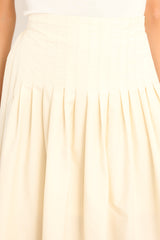 Close up view of this skirt that features a high waisted design, an elastic insert at the back of the waist, and intricate pleats around the hipline.