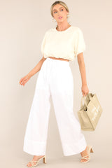 This ivory top features a crew neckline, elastic cuffed dolman sleeves, and an elastic cuffed cropped hemline.