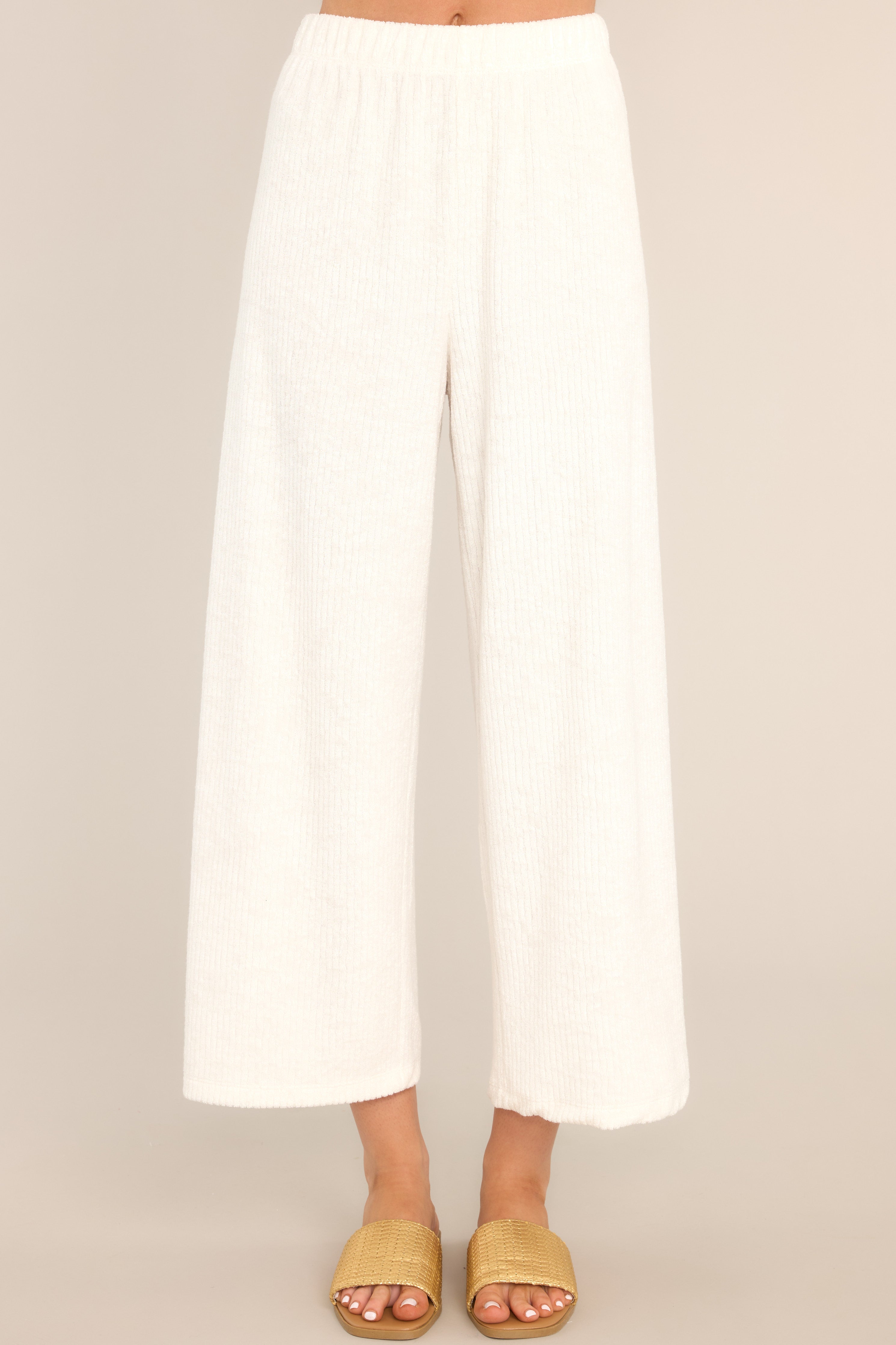 Close up view of these pants that feature a high waisted design, an elastic waistband, ribbed terry cloth, and a slightly cropped hemline.