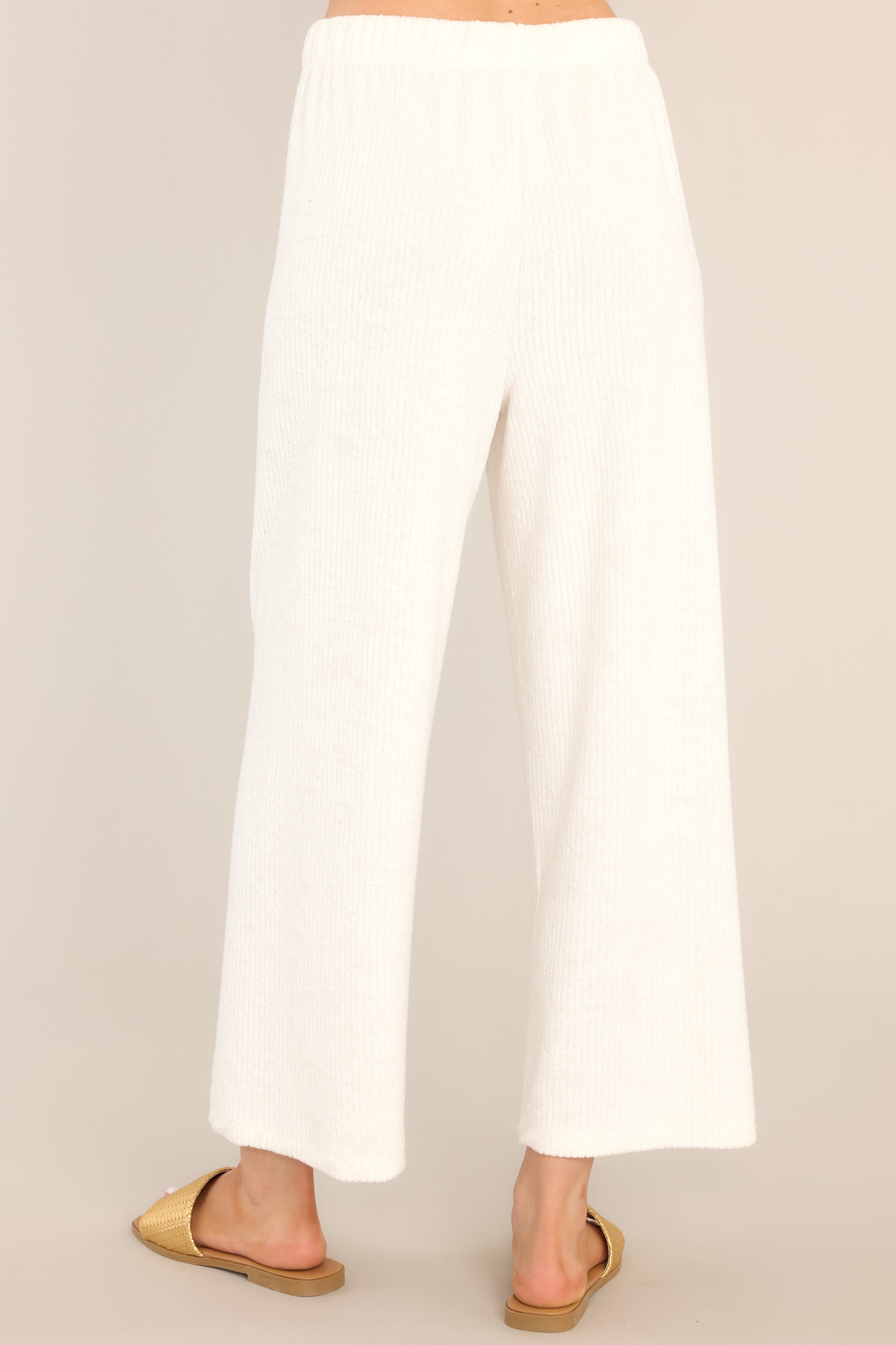 Back view of these pants that feature a high waisted design, an elastic waistband, ribbed terry cloth, and a slightly cropped hemline.