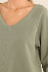 Close up view of this sweatshirt that features a ribbed wide v-neckline, an intentional front-seam detail, fitted ribbed sleeve cuffs, a small split hem on the sides, and an open v-shaped back detail. 