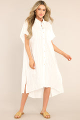 Full body view of this dress that features a collared neckline, a chest pocket, wide sleeves, a button front, a textured material, a front slit, and a split high-low hemline.