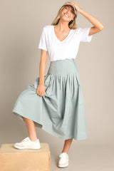 This blue skirt features a high waisted design, an elastic insert at the back of the waist, and intricate pleats around the hipline.
