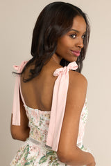 The back of this lace, peach floral dress features a zipper down the middle and peach ribbon straps. 