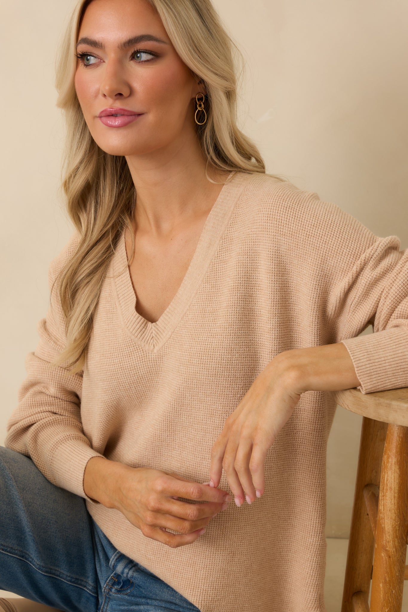 Cropped view of light taupe sweater emphasizing V-neckline, ribbed cuffs, and soft knit fabric.